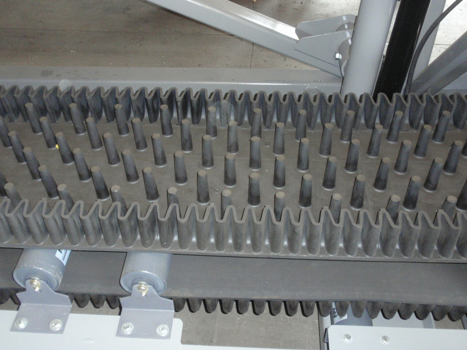 Corrugated CamFlex belt with molded conical nubs running through a conveyor frame